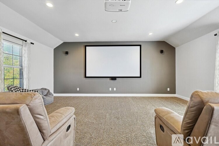 A home theater room with a large screen and comfortable seating.