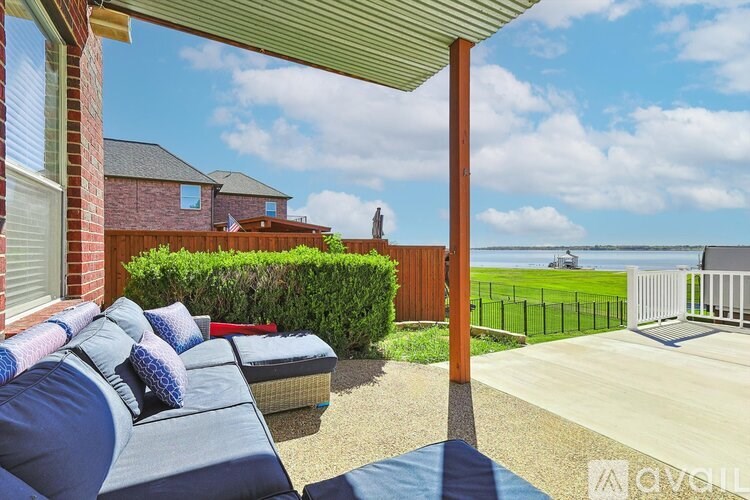 A patio with a couch and a table is covered by a roof.