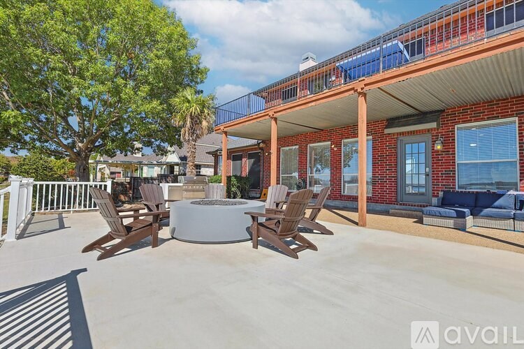 A patio with a fire pit and chairs.