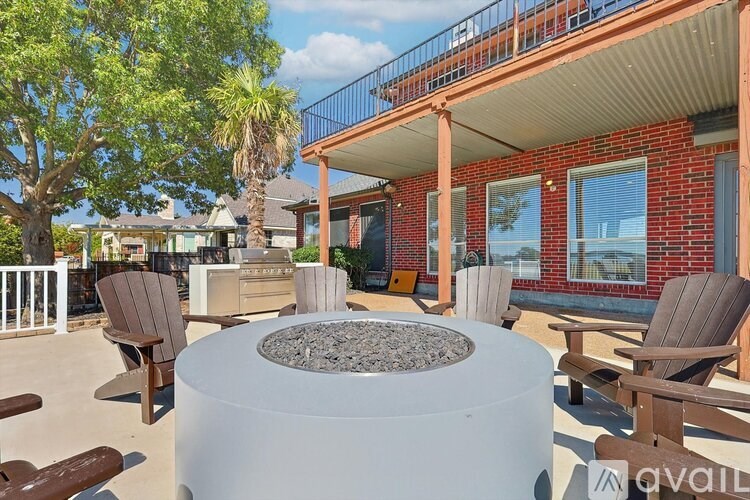 A patio with a fire pit and chairs.