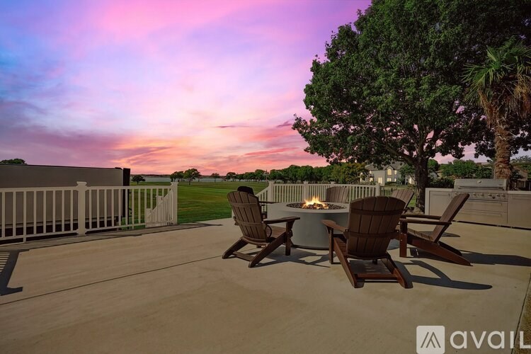 A patio with two chairs and a table with a fire pit in the middle.