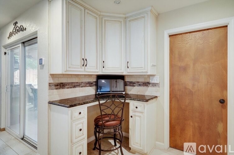 A kitchen with white cabinets and a wooden door.