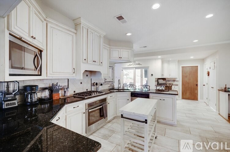 A kitchen with white cabinets and black countertops.