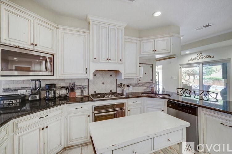 A kitchen with white cabinets and black countertops.