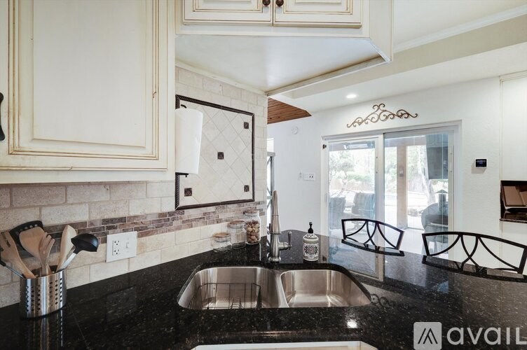A kitchen with a black counter top and white cabinets.