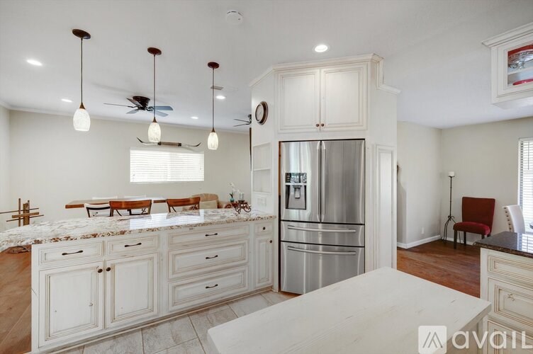A kitchen with white cabinets and a stainless steel refrigerator.