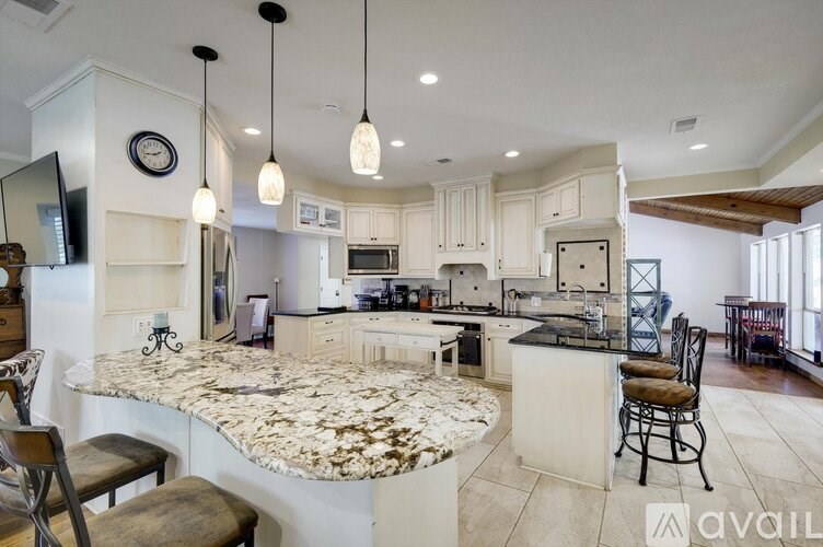 A kitchen with a marble island and pendant lights.