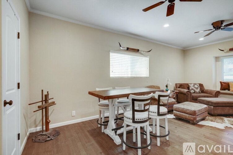 A room with a dining table and chairs in the center and a couch in the corner.