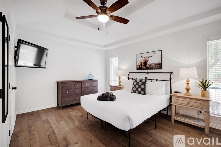 A bedroom with a bed, dresser, and ceiling fan.