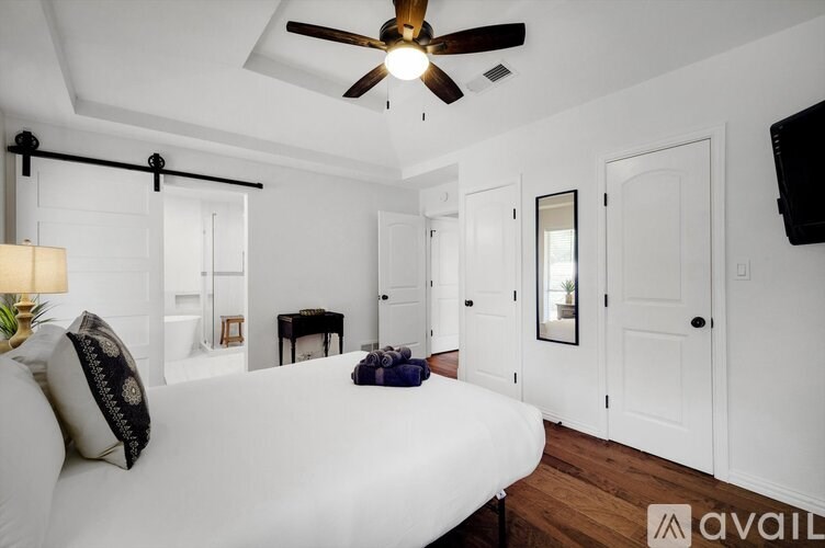 A bedroom with a bed, a ceiling fan, and a television.