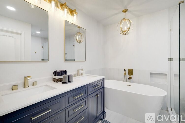A bathroom with a white tub and a large mirror above the sink.