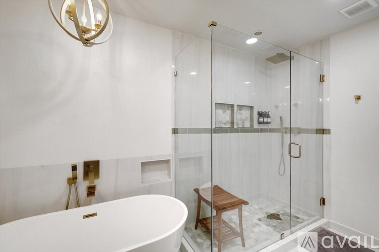 A modern bathroom with a white tub and a glass shower stall.