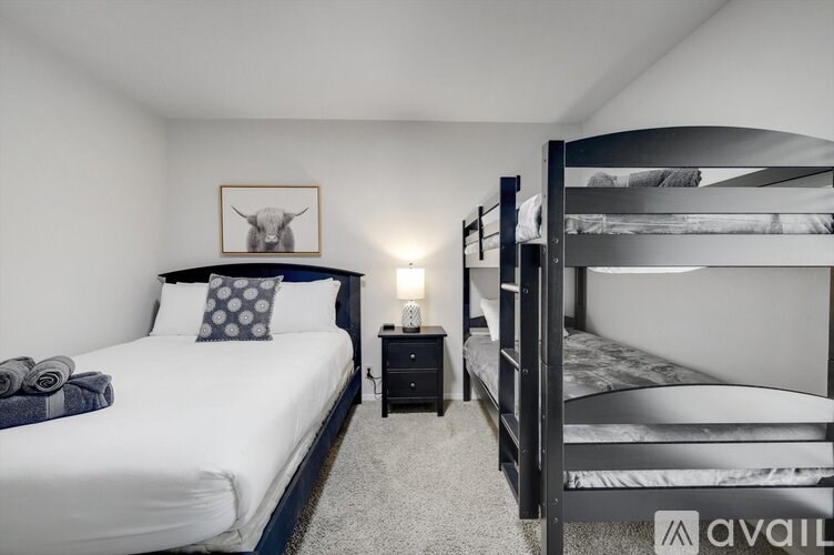 A bedroom with a white bed and a bunk bed with a grey blanket.