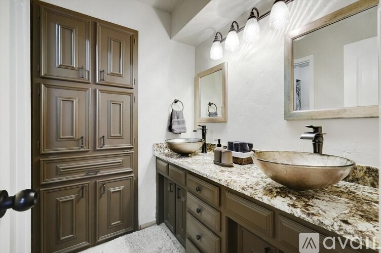 A bathroom with a brown wooden door and a marble countertop.