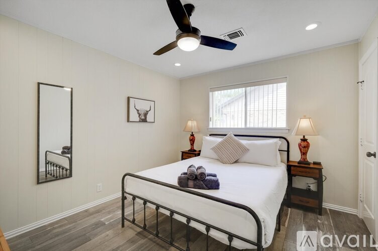 A bedroom with a bed, two lamps, and a ceiling fan.