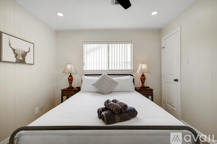 A bedroom with a large bed, two lamps, and a painting of a bull's head on the wall.