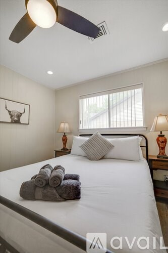 A bedroom with a bed, two lamps, and a ceiling fan.