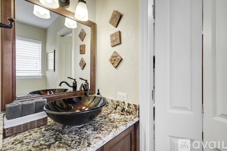 A bathroom with a granite countertop and a black bowl sink.