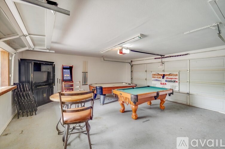 A room with a pool table, a chair, and a billiard table.