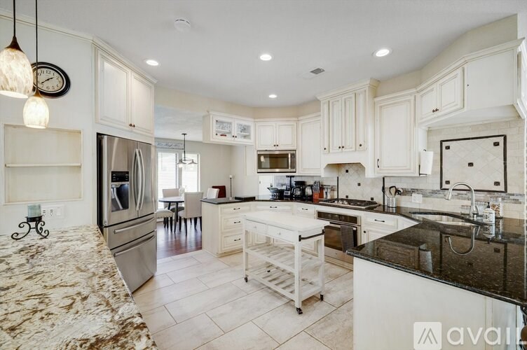 A kitchen with white cabinets and a black fridge.