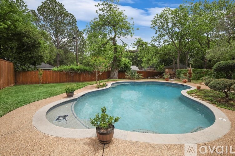 A small round pool surrounded by a concrete border and a wooden fence.