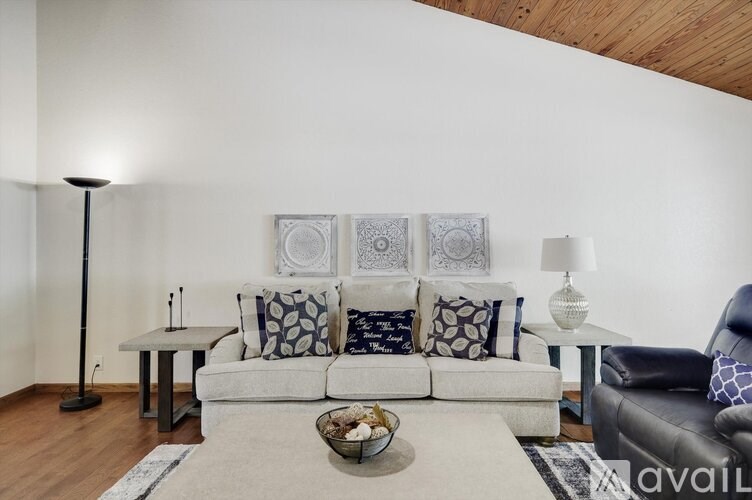 A living room with a white couch, a black floor lamp, and a white side table with a lamp.
