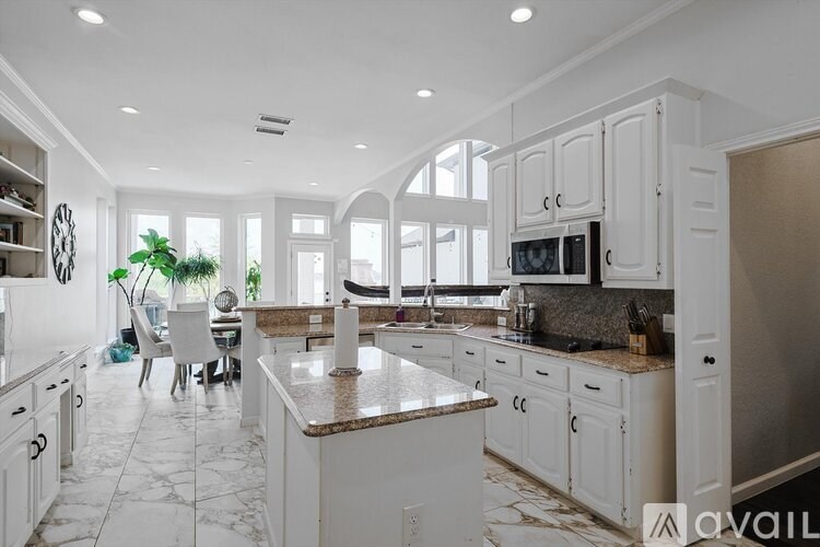 A kitchen with white cabinets and a marble countertop.