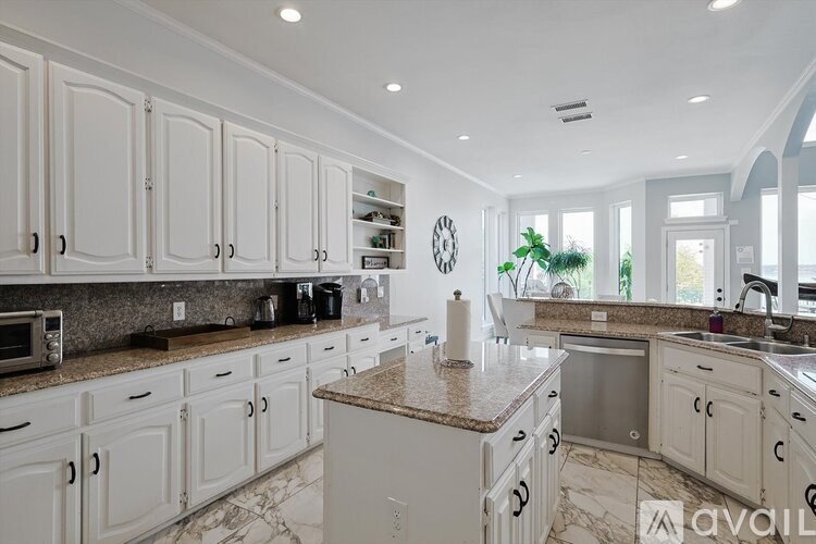 A kitchen with white cabinets and a marble countertop.