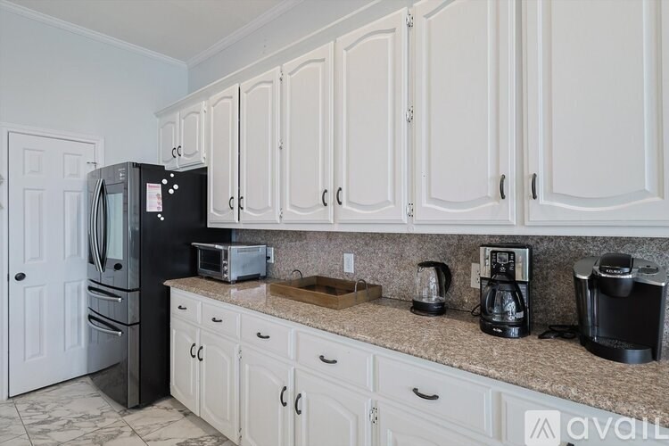 A kitchen with white cabinets and a granite countertop.