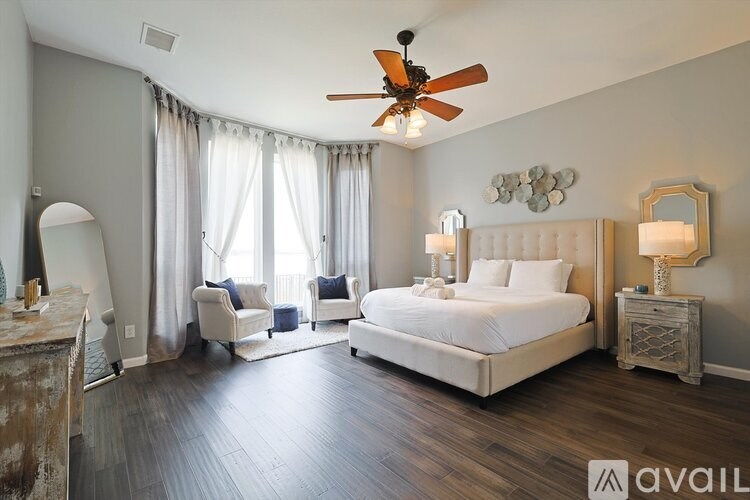 A bedroom with a large bed, a chair, and a dresser.
