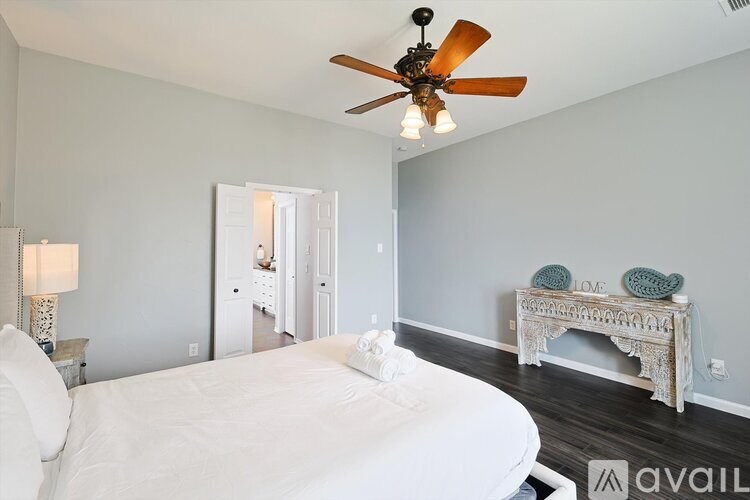 A bedroom with a white bed and a ceiling fan.
