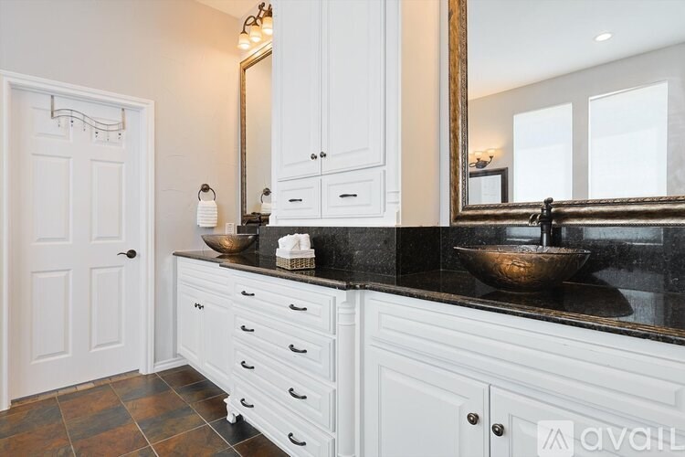 A bathroom with a sink, mirror, and cabinets.