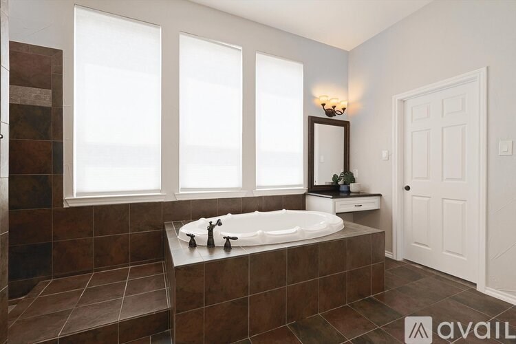 A bathroom with brown tiles and a large tub.