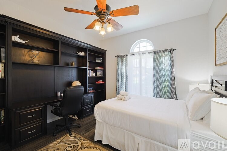 A bedroom with a bed, desk, and bookshelf.