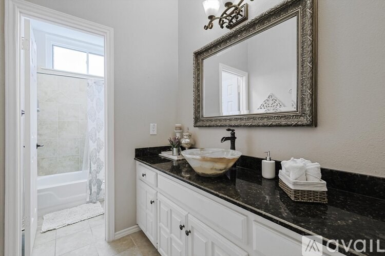 A bathroom with a sink, mirror, and a shower.