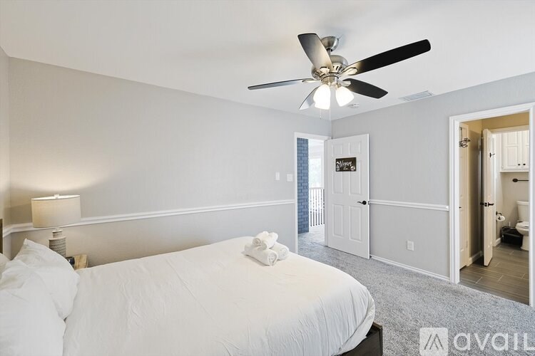 A bedroom with a bed, a ceiling fan, and a nightstand with a lamp.