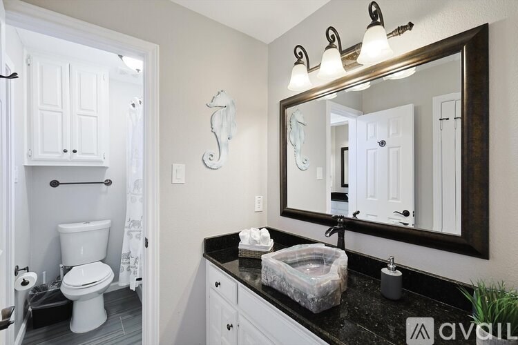 A bathroom with a toilet, sink, and mirror.