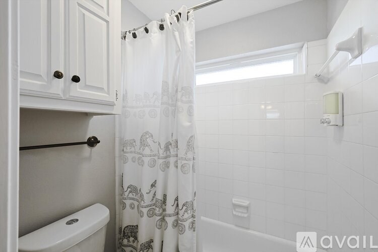 A white bathroom with a shower curtain and a toilet.
