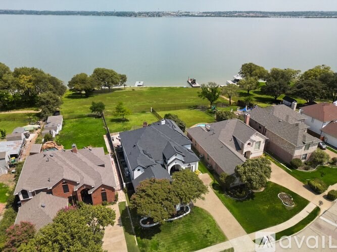 A bird's eye view of a residential area with houses and a body of water in the background.