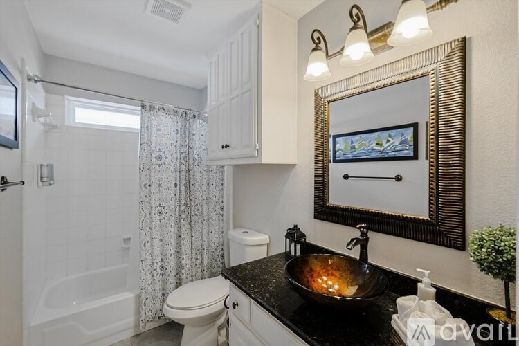 A bathroom with a black countertop and a white toilet.