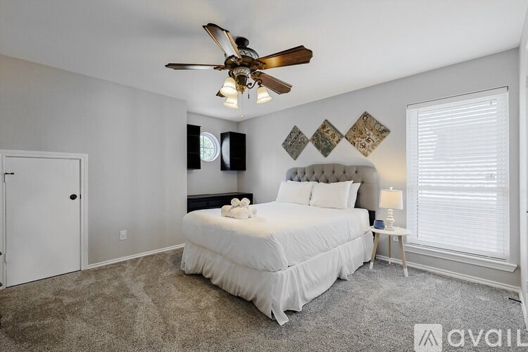 A bedroom with a large bed and a ceiling fan.