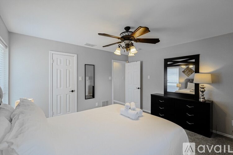 A bedroom with a large bed, a dresser, and a ceiling fan.