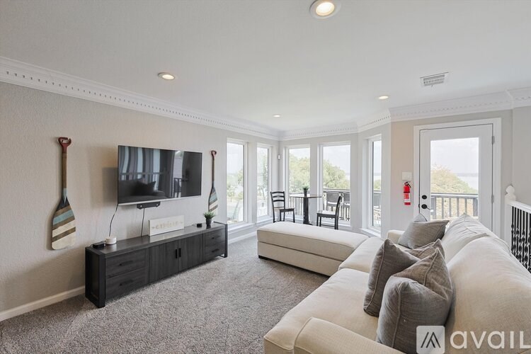 A living room with a white couch and a television on a black stand.