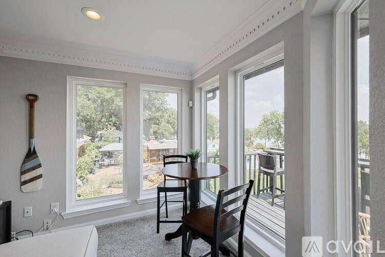 A room with a table and chairs in front of a window.