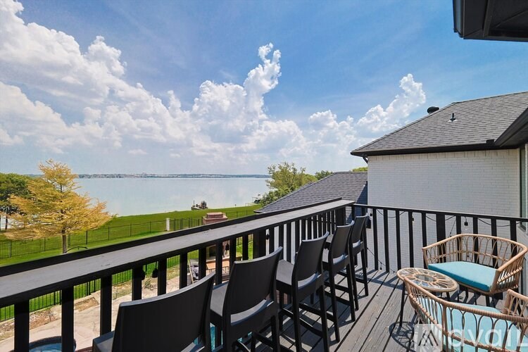 A balcony with chairs and a table overlooking a body of water.