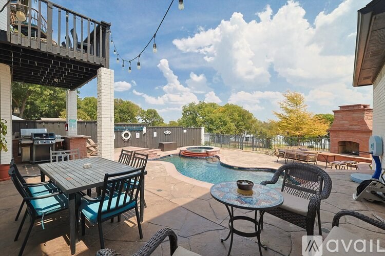 A patio with a table and chairs overlooking a pool.