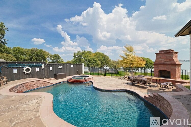 A large outdoor swimming pool with a hot tub and a fireplace.