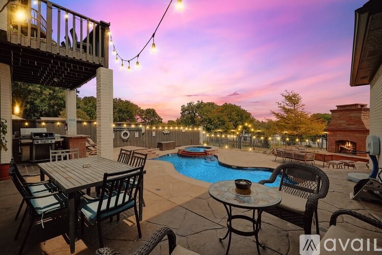 A patio with a table, chairs, and a pool surrounded by lights.