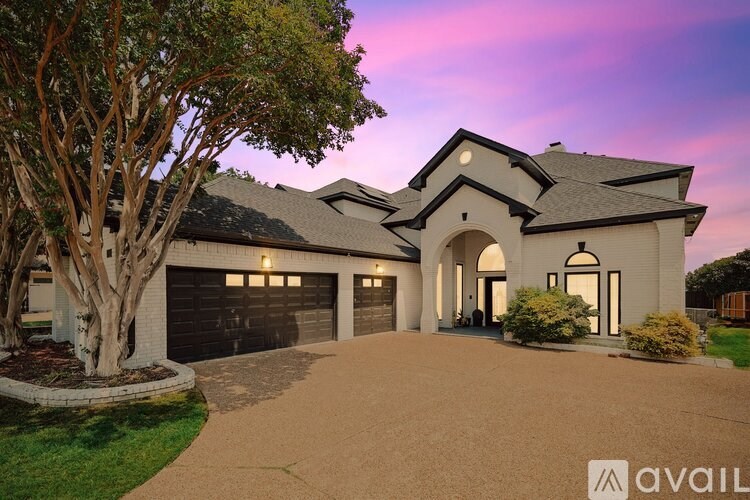 A house with a driveway and a tree in front of it.