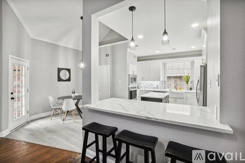 A kitchen with a bar and stools in front of a large mirror.
